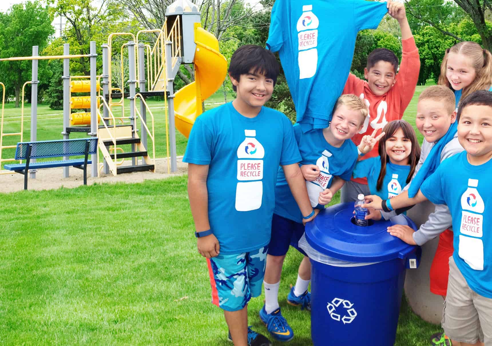 Children at a school hold up "Please Recycle" t-shirts at a PepsiCo Recycle Rally event.